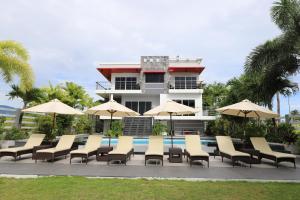 een zwembad met stoelen en parasols voor een gebouw bij The Lighthouse in Puerto Galera