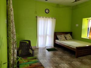 1 dormitorio con 1 cama y reloj en la pared en CoralbayFarms en Chengalpattu