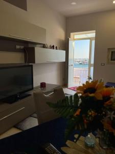 uma sala de estar com televisão e um vaso de flores em Casa Marina em Sciacca