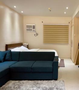 sala de estar con sofá azul y cama en Studio Type - Matina Enclaves Residences en Dávao