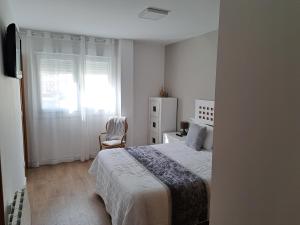ein Schlafzimmer mit einem Bett, einem Stuhl und einem Fenster in der Unterkunft Apartamento Calvarios in Sanxenxo