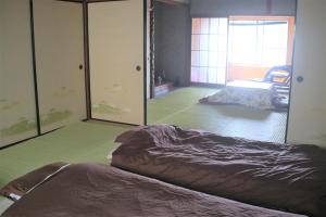 a bedroom with a bed and a room with a mirror at ゲストハウスさくら Guesthouse Sakura in Sukumo
