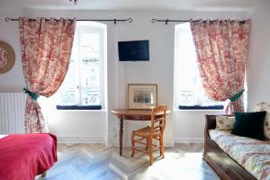 um quarto com uma mesa e uma cadeira e duas janelas em La Domerie - Maison d'hôtes em Aubrac