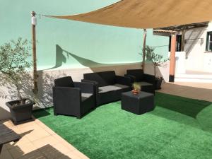 a patio with a couch and a table on grass at MariaHouse in Faro