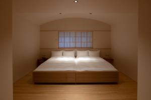a bedroom with a bed with white sheets and a window at Tsukihitei in Nara