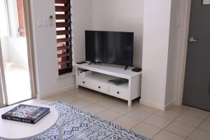 a living room with a television on a white cabinet at Clifton Beach Retreat - 2 bed 2 bath apartment in Clifton Beach