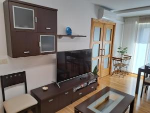 ein Wohnzimmer mit einem TV und einem Tisch in der Unterkunft APARTAMENTO GUIMAREY in Sanxenxo