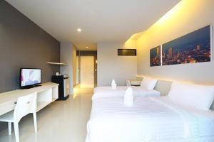 a bedroom with two beds and a desk and a tv at Hatyai Signature Hotel in Hat Yai