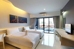 una camera d'albergo con 2 letti, una scrivania e una TV di Hatyai Signature Hotel a Hat Yai