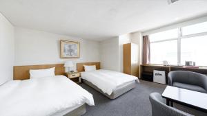 una habitación de hotel con 2 camas y una silla en Tabist THE GREEN ASAHIKAWA, en Asahikawa