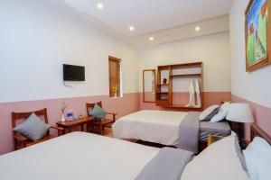 Cette chambre comprend 2 lits et une télévision. dans l'établissement An Hiên Homestay Hội An, à Hội An