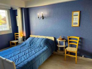 - une chambre bleue avec un lit et deux chaises dans l'établissement Bel appartement à deux pas de la plage, à Le Touquet-Paris-Plage