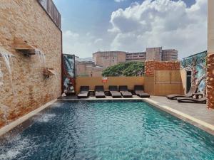 una piscina en la azotea de un edificio con sillas en Hotel De Khuvieng, en Chiang Mai