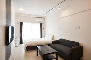 sala de estar con cama y sofá en New Normal Hotel in NAGO ニューノーマルホテルイン名護, en Nago