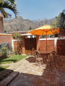 un patio con mesa, sillas y sombrilla en Azomalli en Tepoztlán