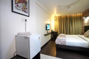 a hotel room with a bed and a refrigerator at Hotel Singh`s By WB Inn, Vashi, Navi Mumbai in Navi Mumbai