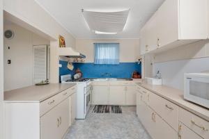 a kitchen with white cabinets and a blue wall at Beach view Rippleside Cottage in Geelong West