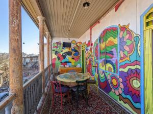 un balcón con mesa y sillas y una pared colorida en Namaste Hostel en Tiflis