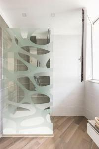 a glass shower door in a bathroom with wooden floors at Villa Vanessa Milazzo, Sicily - EV Charge Station in Milazzo