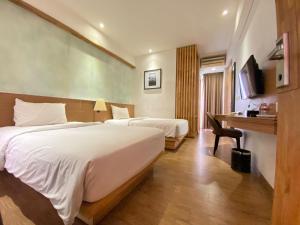 a hotel room with two beds and a desk at Liberta Hotel Jimbaran in Jimbaran