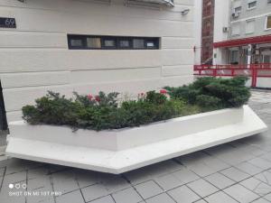 un banc blanc avec des plantes à côté d'un bâtiment dans l'établissement Apartman Biblioteka, à Novi Beograd