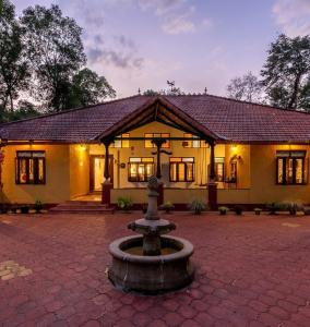 a building with a fountain in front of it at amã Stays & Trails, Rare Earth Estate in Madikeri