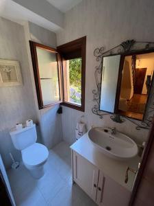 uma casa de banho com um WC, um lavatório e um espelho. em Chalet Adosado en exclusiva urbanización em Comillas
