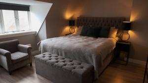 a bedroom with a large bed and a chair at 't Sand Apartment in Zandvoort