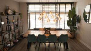 une salle à manger avec une table et quatre chaises vertes dans l'établissement 't Sand Apartment, à Zandvoort