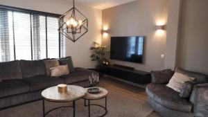 un salon avec un canapé et une télévision dans l'établissement 't Sand Apartment, à Zandvoort