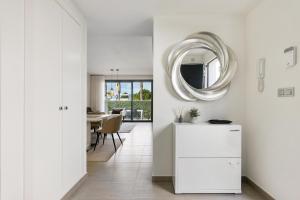 biała kuchnia z lustrem i stołem w obiekcie CB Living - 3 bedroom home in Punta Prima w mieście Torrevieja