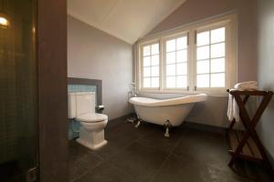 a bathroom with a tub and a toilet and a window at Ama Stays and Trails Tea Estate Bungalows , Munnar in Munnar +27 photos