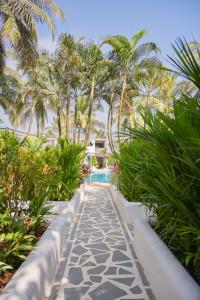 a walkway with palm trees and a swimming pool at Soul Vacation Resort and Spa,Colva in Colva