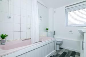 a bathroom with a pink tub and a toilet at Fairlands lodge in Stevenage