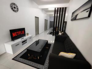 a living room with a black couch and a television at Homestay Temerloh Near Hospital Wi-Fi Netflix in Temerloh