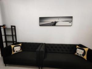 a black couch with two pillows on a white wall at Homestay Temerloh Near Hospital Wi-Fi Netflix in Temerloh