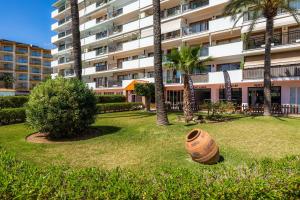 a large building with palm trees and a pot in a yard at Apartamento Vista Mar in Alcudia