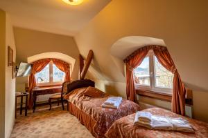 a bedroom with two beds and a desk and two windows at Willa Barbara - ProHarmonia in Lądek-Zdrój