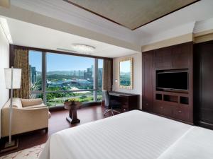 Futian Shangri-La, Shenzhen,Near to Shenzhen Convention&Exhibition Centre, Futian Railway Station في شنجن: غرفة نوم بسرير ومكتب وتلفزيون