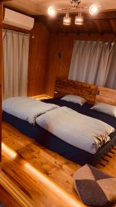 two beds in a room with wooden floors at Yamato inn - Vacation STAY 86368v in Amami