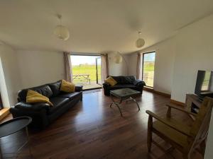 a living room with a black couch and a table at Berryhill East Steading - Sleeps 6 - Peterhead - Dog Friendly - Rural Location -Smart TV - Golf Driving Range - EV Point in Peterhead