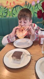Um rapaz a comer um pedaço de bolo numa mesa. em camere de închiriat Duly Costinești em Costinesti