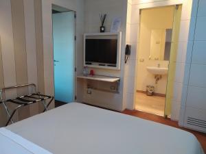 1 dormitorio con 1 cama, TV y lavamanos en Molo73 en Empoli