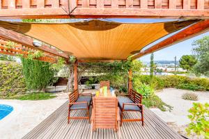 um pátio com uma mesa e cadeiras sob uma pérgola em Villa Demiana by Ezoria Villas em Coral Bay