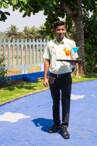 a man holding a tray with a drink on it at Palmarinha de Goa in Calangute