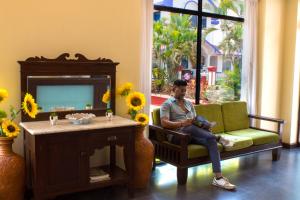 a man sitting in a chair next to a table with sunflowers at Palmarinha de Goa in Calangute