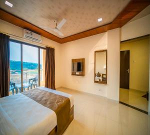 a bedroom with a large bed and a large window at Vrindavan Resort in Mahabaleshwar