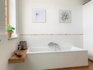 eine Badewanne in einem weißen Badezimmer mit zwei Bildern an der Wand in der Unterkunft Fe Wo Brunnen - 120 qm- ruhige Lage - viel Natur - komfortabel - grosser Balkon und Garten in Memmingen