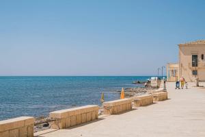 a boardwalk next to the ocean with people walking on it at Hotel Le Dune in Sampieri