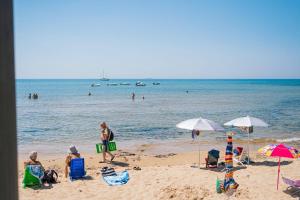 a group of people sitting on the beach at Hotel Le Dune in Sampieri